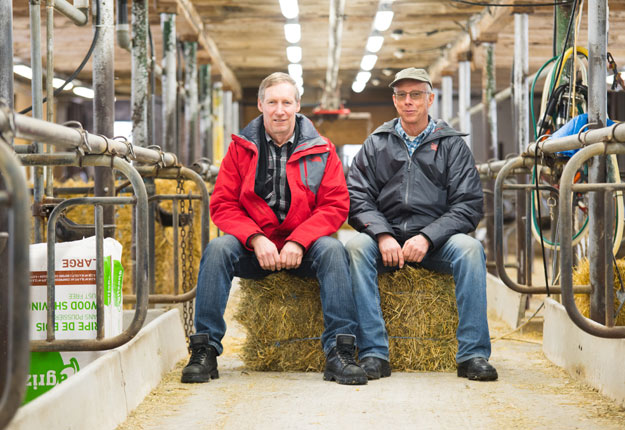 Gilbert et Simon Halde posent dans leur étable vide, où se trouvaient des vaches depuis 71 ans. Crédit photo: Martin Ménard / TCN