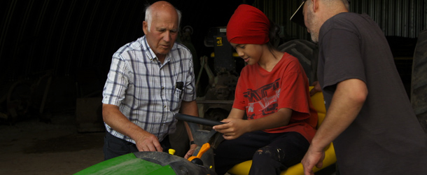 Avant de passer aux gros tracteurs, Nathan, le petit gars de la ville, est initié par son grand-père Jean-Guy et son oncle Jean à la conduite du tracteur à gazon. Ils représentent la 3e, 4e et 5e génération de Martin à la ferme familiale. Crédit photo : Gracieuseté de Télé-Québec