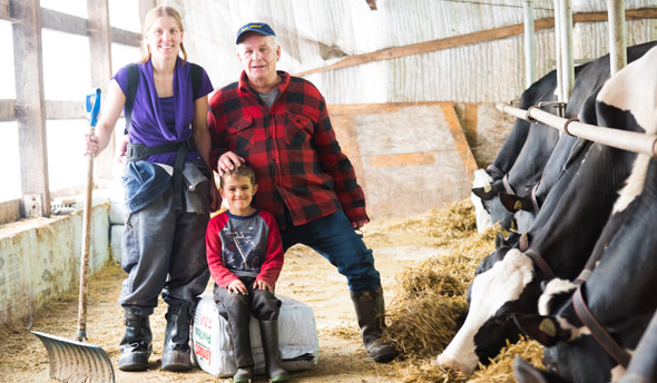 Une photo de famille non apparentée : Jacques Massé transfère sa ferme à Émilie Ménard et son conjoint. « Il nous donne une chance. Il nous a offert un premier bloc de parts dans l’entreprise contre de “l’huile de coude” et du bon vouloir », explique Émilie. Crédit photo : Martin Ménard/TCN