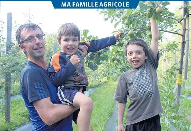 Frédéric Dallaire, propriétaire de la ferme La pointe-aux-pommes, en compagnie de ses garçons Mathis et Oli. Bien qu’ils ne soient pas encore prêts à aider leur père dans ses tâches, cela ne saurait tarder. Photo : Charles-Olivier Caron