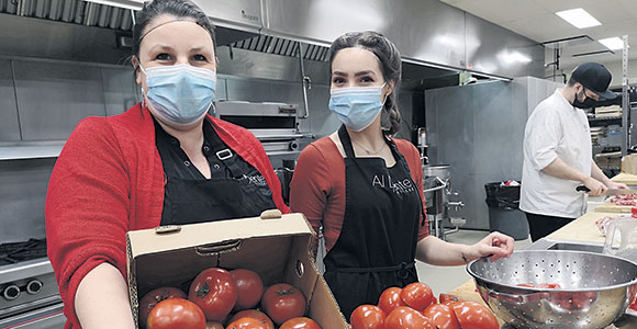 Les bénévoles ont produit quelque 500 paniers fermiers dans les cuisines de l’Académie hôtelière de Charlevoix à La Malbaie. Parmi eux, Julie Bouchard, copropriétaire d’Al Dente Traiteur, et la jeune Monika Pando, 19 ans. « J’ai trouvé ça super de voir autant de personnes donner de leur temps et de leur énergie pour faire plaisir à des gens dans le besoin! » a commenté Monika. Photo : Karine Dufour Caucho
