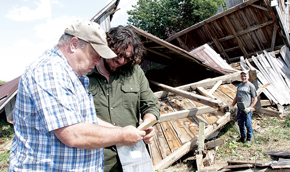 Dwight Cullen (à gauche) montre au démolisseur-récupérateur David Rémillard l’article publié dans un journal local en 1960 racontant comment l’étable a été transportée jusqu’à sa ferme de Howick.