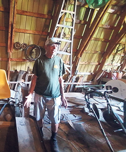 Luc Forget explique le fonctionnement de la semeuse fabriquée à partir d’un vieil instrument presque centenaire et de tuyaux de sécheuse. Photo : Claude Fortin