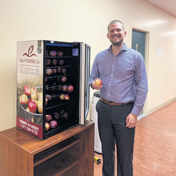 Ce réfrigérateur de pommes gratuites fait partie des actions mises en place pour retenir les employés et en attirer d’autres. Sur la photo, le directeur des ressources humaines de la Fédération de l’UPA du Centre-du-Québec, Maxime Sauvageau. Photo : Marie-Soleil Blain