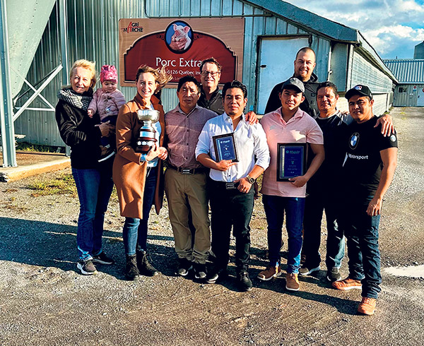 Kim Loranger tient la Coupe Kenlis, entourée des membres de sa famille et des employés de la Ferme Porc Extra. Photo : Gracieuseté de Porc Extra